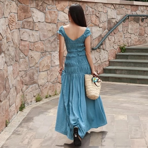 Détail d'une robe bleue avec dos en V, plis et jupe à volants sur un mannequin dehors