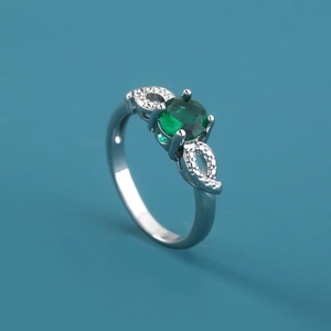 Close-up of silver ring with round green gemstone and hollow zircon-set band detailing