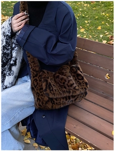 Bolso de hombro de piel sintética con estampado de leopardo llevado por una modelo en el parque