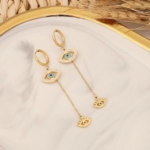 Golden stainless steel long drop evil eye earrings with zircons on marble background