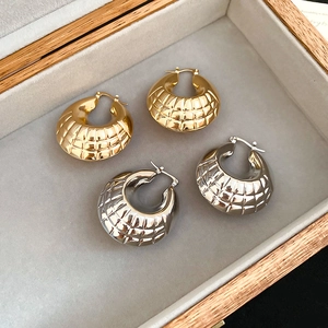 Detail of textured geometric hoop earrings with rhombic pattern in gold and silver