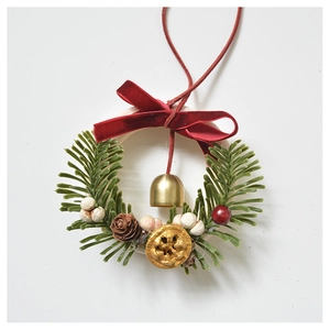 Christmas wreath detail with red velvet bow, golden bell, pine needles and berries