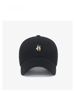 Front detail of black cotton baseball cap featuring gold letter embroidery and twill fabric