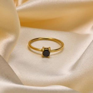 Detail of a gold titanium ring featuring a black round zircon in a classic 4-prong setting