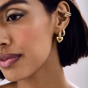 Fashionable 18k gold heart earrings set with zircon cuff on female model ear