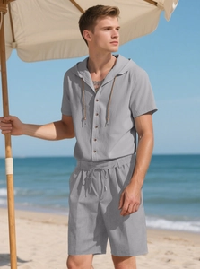Detail of men's grey linen hooded shirt and shorts set worn on a sunny beach