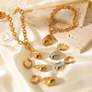 Parure de bijoux chic or et argent avec pendentifs gouttes sur fond de soie et de pierre