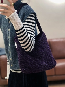 Dettaglio di una borsa tote in tweed viola spesso con trama a maglia grossa ed etichetta del marchio
