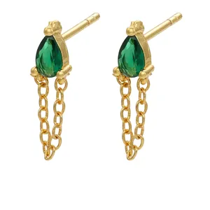 Detail of gold-plated brass earrings with pear-cut green gemstones and fine chain drops