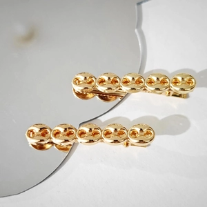 Two vintage gold chain-link hair clips displayed on a decorative mirror for women