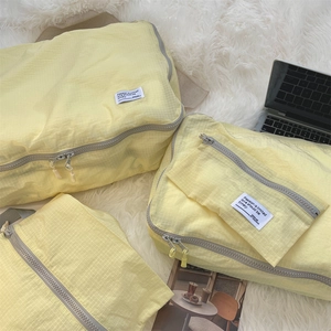 Flat lay of yellow travel storage bags with grid texture on a white faux fur rug