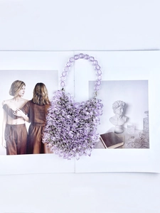 Detail of a handmade purple beaded handbag with transparent faceted beads on a magazine