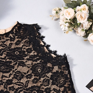 Detail shot of black floral lace fabric with delicate eyelash trim on a slim romper