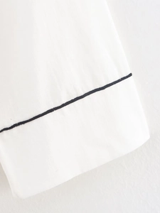 Detailed view of white cotton-linen fabric with contrasting black piping trim edges