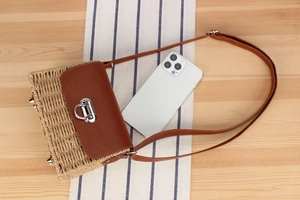 Detail of paper straw crossbody bag with brown leather flap and silver turn-lock closure