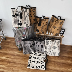Collection of large canvas tote bags with aesthetic letter prints on a silver suitcase