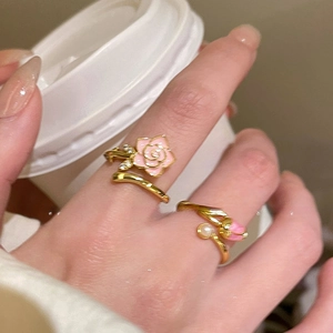 Detail of 18k gold plated pink enamel flower rings with pearls on model hand