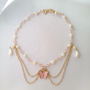 Detail of multi-layer gold chain necklace with pink crystal beads and butterfly pendant