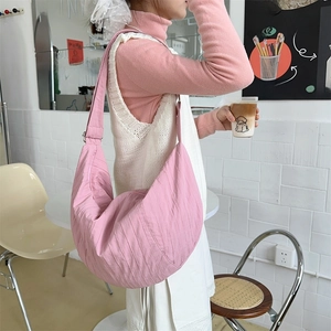 Close-up of pink pleated crescent bag with textured polyester fabric and adjustable strap