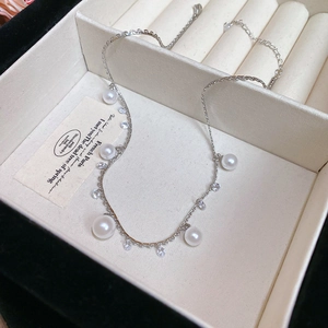 Detail view of pearl and tassel necklace on a beige jewelry box with elegant lighting