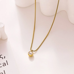 Detailed close-up of a golden box chain necklace with a sparkling round zircon pendant