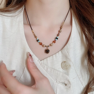 Close-up of vintage tiger eye heart pendant with colorful beads on a brown cord necklace