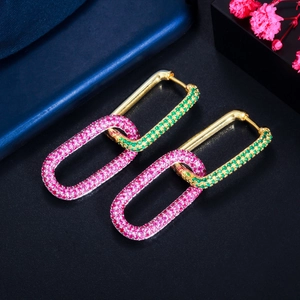 Macro detail of gold geometric hoop earrings with pink and green pavé zircons