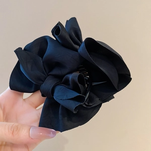 Detail of elegant black fabric bow hair claw clip with multi-layered pleated design
