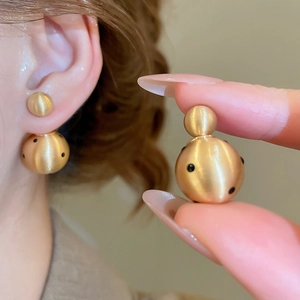 Macro detail of 18k gold plated ball earrings with matte finish and black polka dots