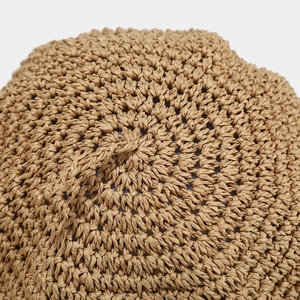 Close-up of hand-woven straw beret showing spiral weave texture and natural fiber detail