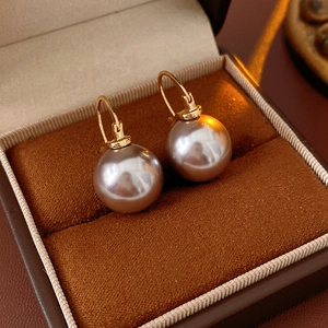 Close-up of grey pearl earrings with golden hoops in a brown velvet jewelry box
