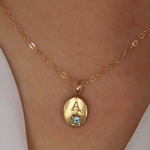 Vue détaillée du pendentif ovale plaqué or 18 carats avec lettre A et zircon bleu