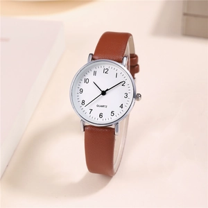Macro shot of minimalist white dial quartz watch with brown leather strap and silver case