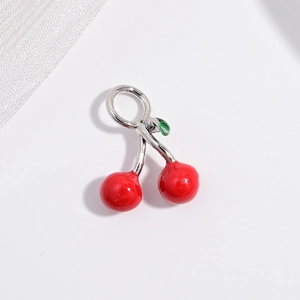 Detail of red cherry pendant with silver stem and green leaf on white mesh background