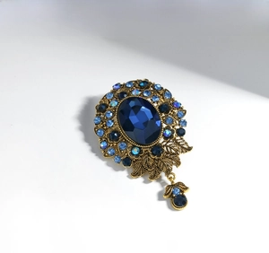 Detailed close-up of Victorian style brooch with deep blue gemstone and rhinestones