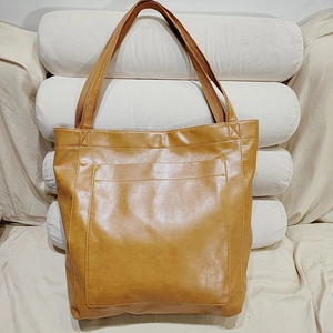 Gros plan d'un cabas vintage en cuir ciré marron avec grande poche avant et longues anses