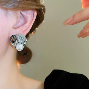 Détail de boucles d'oreilles rose avec perles blanches et gemmes sur le modèle