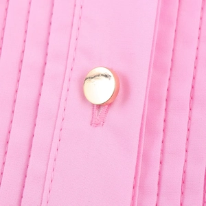 Macro detail of pink poplin dress featuring golden button and elegant pin-tuck pleats