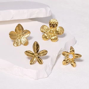 Minimalist gold floral stainless steel stud earrings set on a white stone background