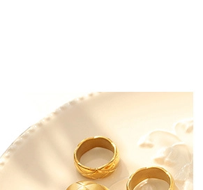 Close-up of golden quilted texture ring on a ceramic plate with soft warm lighting
