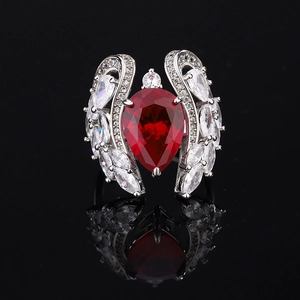 Macro shot of silver ring with pear-shaped red gemstone and white angel wing accents