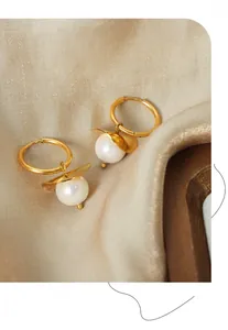 Detail of 18K gold-plated earrings with lustrous lavender pearls on silk fabric