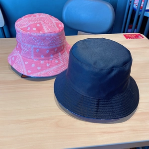 Detail view of pink paisley pattern and navy blue reversible cotton bucket hats