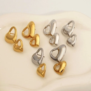 Orecchini a cuore traforato in acciaio 316 oro e argento su un vassoio bianco