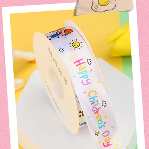 Detail of Happy Children's Day satin ribbon with colorful prints on a beige spool