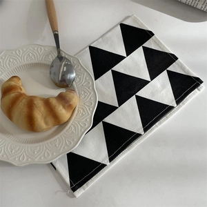 Makroaufnahme der geometrischen schwarz-weißen Tischmatte mit Croissant und elegantem Teller