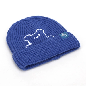 Close-up of blue ribbed knit beanie featuring white embroidered bear and side logo tag
