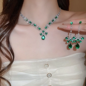 Close-up of emerald green square drop necklace and earrings set worn by a model