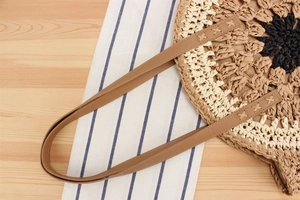 Detailed view of handmade straw tote bag with floral pattern and leather shoulder straps
