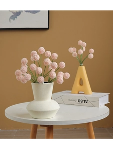 Detail of pink artificial billy balls in a white minimalist ceramic vase on a table